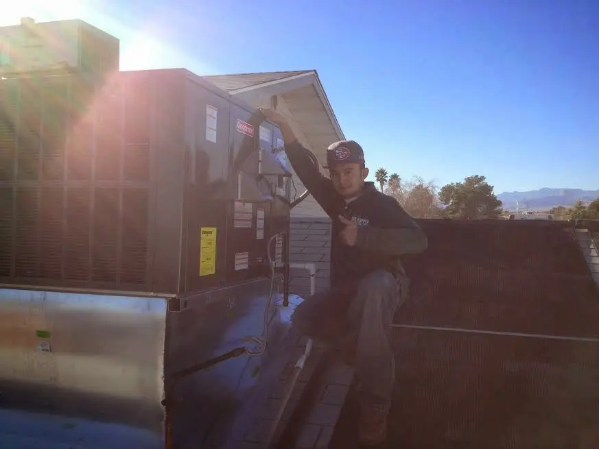 HVAC technician performing AC Tune-Up on a rooftop unit in Highgrove